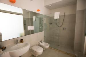 a bathroom with a sink and a toilet and a shower at Cave Bianche Hotel in Favignana