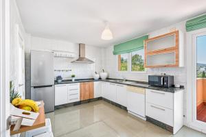 a kitchen with white cabinets and a large window at Ático Playa de los Álamos in Torremolinos