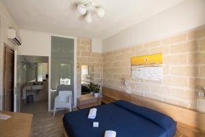 a bedroom with a blue bed and a bathroom at Cave Bianche Hotel in Favignana