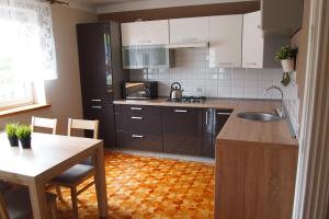 uma cozinha com armários brancos, uma mesa e um lavatório em Spiski Apartament em Comuna de Łapsze Niżne