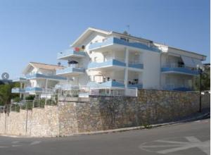 un gran edificio de apartamentos blanco en una pared de piedra en Residence Horisontis, en Pineto