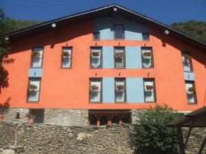 an orange building with potted plants in the windows at Masia d'en Valentí in Anserall