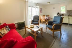 a living room with a red couch and chairs and a table at Gîte le Noyer - l'Ancien Vignoble in Saint-Julien-de-Lampon