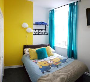 a bedroom with a bed with yellow walls and a window at The Moray House in Blackpool