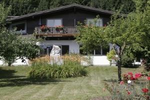 a house with a balcony and a yard with flowers at Ferienwohnungen Benedikt in Villach