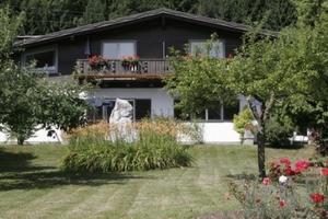 een huis met een balkon en een tuin met bloemen bij Ferienwohnungen Benedikt in Villach