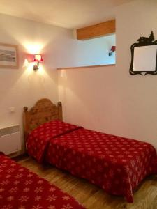 - une chambre avec 2 lits et une couverture rouge dans l'établissement Vacancéole - Résidence Central Park, à La Foux