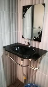ein Bad mit einem schwarzen Waschbecken und einem Spiegel in der Unterkunft Pangkor Home Sea Village in Pulau Pangkor