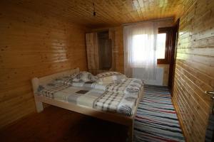 a bedroom with a bed in a wooden room at Cabana Ioana in Munună