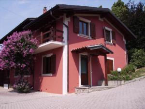 a red house with a tree in front of it at L' Arnia in Ome