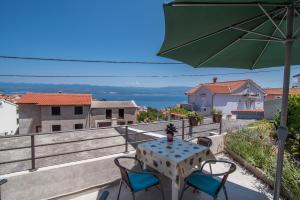 a table and chairs on a balcony with an umbrella at Apartment Andrija in Vrbnik