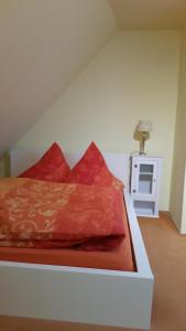 a bed with red pillows on top of it at Haus Isabelle OG in Sankt Andreasberg