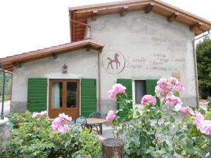 uma pequena casa com persianas verdes e flores rosas em La Fattoria al Crocefisso em Pieve Fosciana