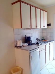 - une cuisine avec des placards blancs et un évier dans l'établissement Marika Garden Studios, à Moraitika