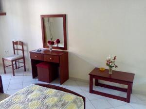 a bedroom with a dresser and a mirror and a table at Marika Garden Studios in Moraitika