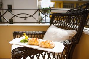 2 pasteles sentados en una silla de mimbre en un balcón en B&B Maiori Luxury, en Maiori