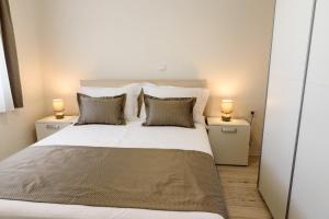 a bedroom with a large white bed with two lamps at Eni apartments BOL in Bol