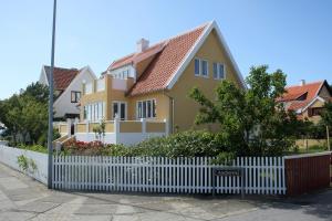 a yellow house with a white picket fence at Østre Strandvej 49 in Skagen