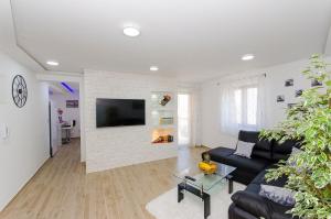a living room with a black couch and a white brick wall at Apartments Keli in Kastel Stari