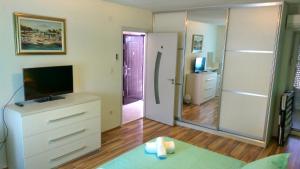a living room with a television and a dresser with a mirror at Apartments Jasminka in Solin