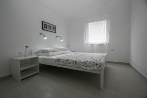 a white bedroom with a bed and a window at Apartmani Popović Nin in Nin