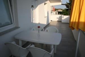 a white table and chairs with a vase on it at Apartmani Popović Nin in Nin