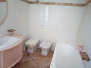 een badkamer met een wastafel, een toilet en een bad bij SA DOMU SARDA CASE VACANZe in Piscinas