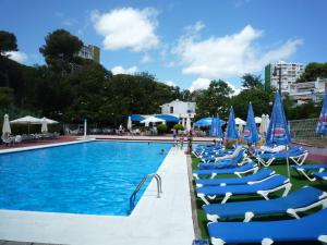 a swimming pool with blue chairs and umbrellas at Tramuntana in Platja d'Aro