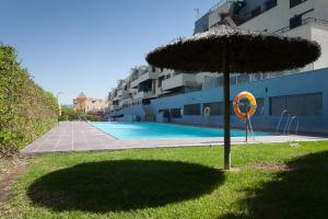 a large umbrella in the grass next to a swimming pool at Lankarifa Apartment in Tarifa