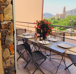 a table with flowers and wine bottles on a balcony at Casale a Figa Bianca in Patrimonio
