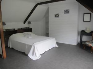 sypialnia z białym łóżkiem i krzesłem w obiekcie Au Clair de la Dune w mieście Frehel