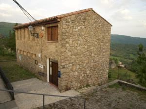 un edificio de piedra con una puerta en una colina en El Corrillo, en Trevejo