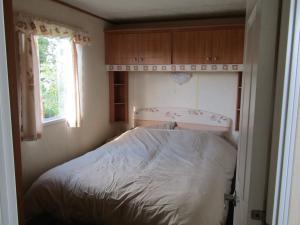 Cama en habitación pequeña con ventana en Fenlake holiday accommodation, en Metheringham