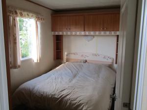 a bed in a small room with a window at Fenlake holiday accommodation in Metheringham