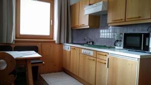 een keuken met houten kasten, een tafel en een magnetron bij Almhof in Sölden +25 foto's