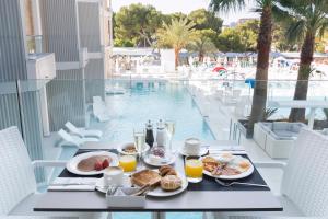 Reverence Mare Hotel - Adults Only في بالمانوفا: طاولة مع طعام الإفطار والمشروبات بجوار حمام السباحة