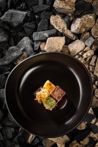 a black plate with food on a stone table at Hotel & Restaurant Rose in Bietigheim-Bissingen