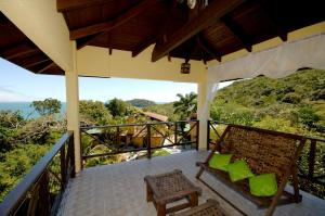 a porch with a bench and a view of the ocean at Pousada Aquarela de Bombinhas in Bombinhas
