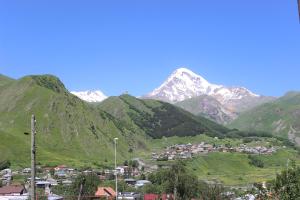 a village in a valley with mountains in the background at Inga Guest House in Stepantsminda