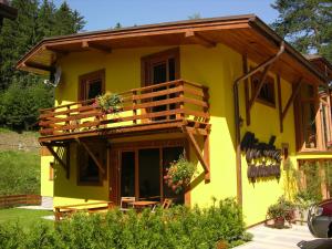 a yellow house with a deck on the side of it at Penzión Jozef a apartmány in Demanovska Dolina