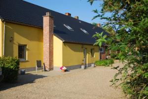 żółty budynek z czarnym dachem w obiekcie B&B Het Uilennest w mieście Bocholt