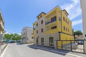 un bâtiment jaune sur le côté d'une rue dans l'établissement Apartments Keli, à Kaštela