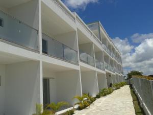 an external view of a white building with palm trees at Residencial Granito e Jasmim in Conde