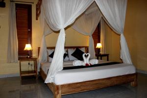 a bedroom with a canopy bed with white drapes at Maha Neka Villa in Sidemen