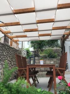 eine Terrasse mit einem Holztisch und Stühlen unter einer Pergola in der Unterkunft Koko Apartments in Korčula