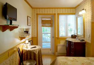 a room with a table and a sink and a window at Auberge des Cévennes in LʼAnse-Saint-Jean