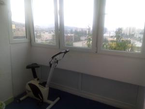 a room with a treadmill in front of three windows at Apartment Alipašino in Sarajevo
