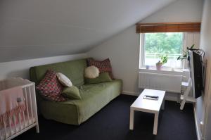 a living room with a green couch and a crib at Annexet på Stallbackens Gård in Ås
