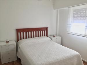 a white bedroom with a bed and a window at F&F Altos de Barracas in Buenos Aires