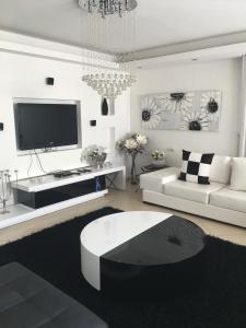 a white living room with a white couch and a tv at Amazing sea view Penthouse close to beach in Ashdod